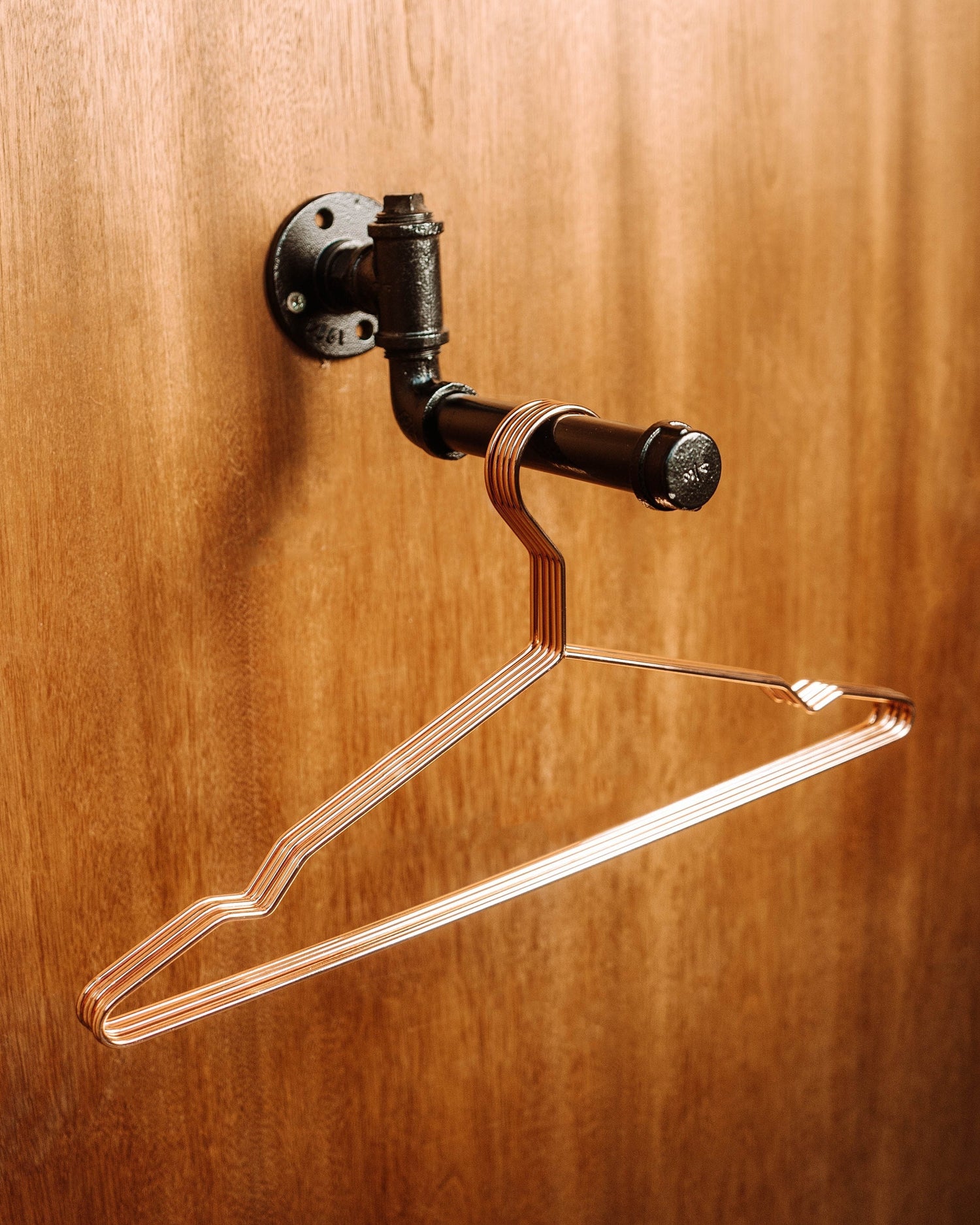 A modern Clothes Rail Wall Mount with hanging garments, offering a space-efficient and stylish way to organize clothing.